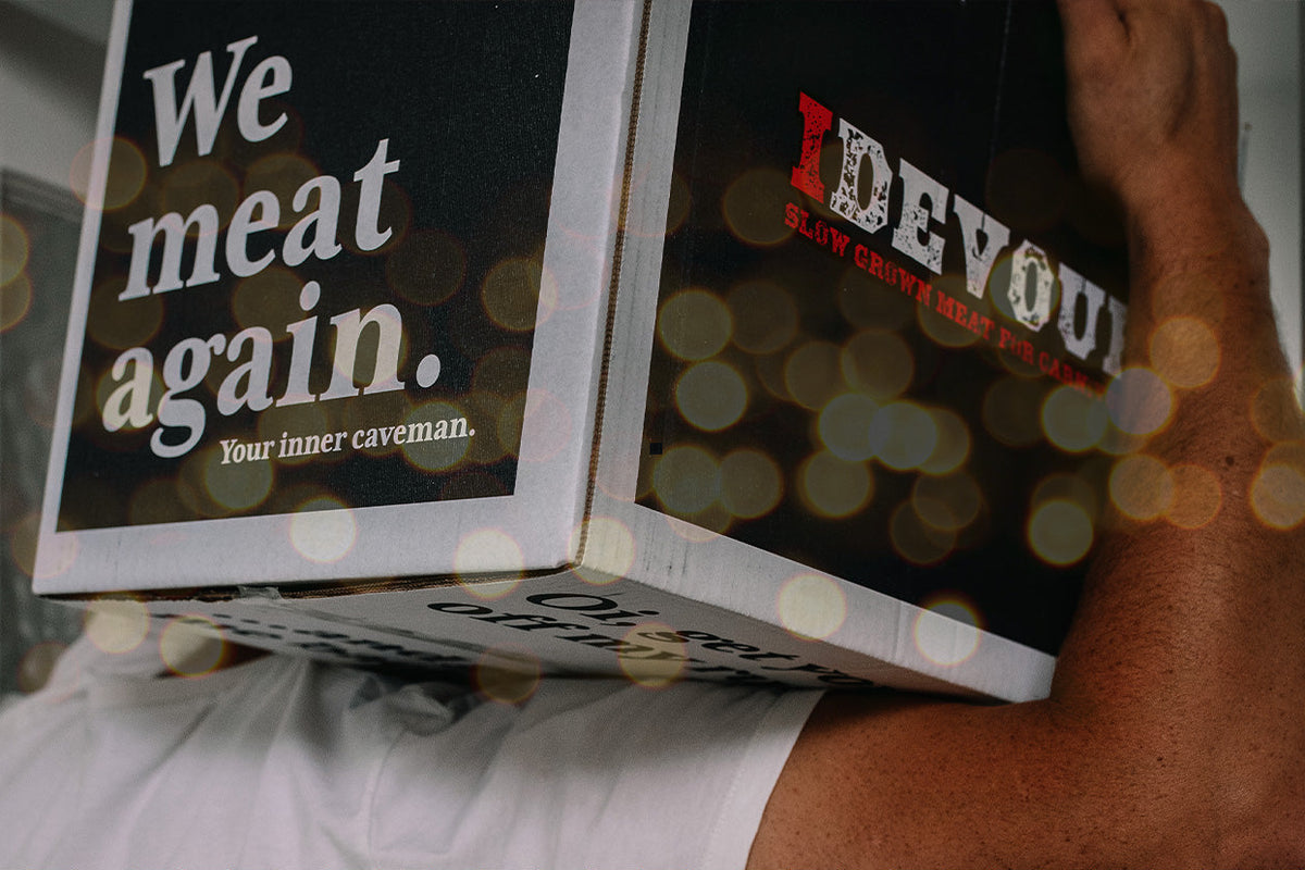 A person carrying a large black Christmas hamper with printed text, shown in a real indoor setting with holiday bokeh lights. The hamper has visible branding and the text 'CHRISTMAS HAMPER - SMALL' appears as an overlaid banner at the bottom.