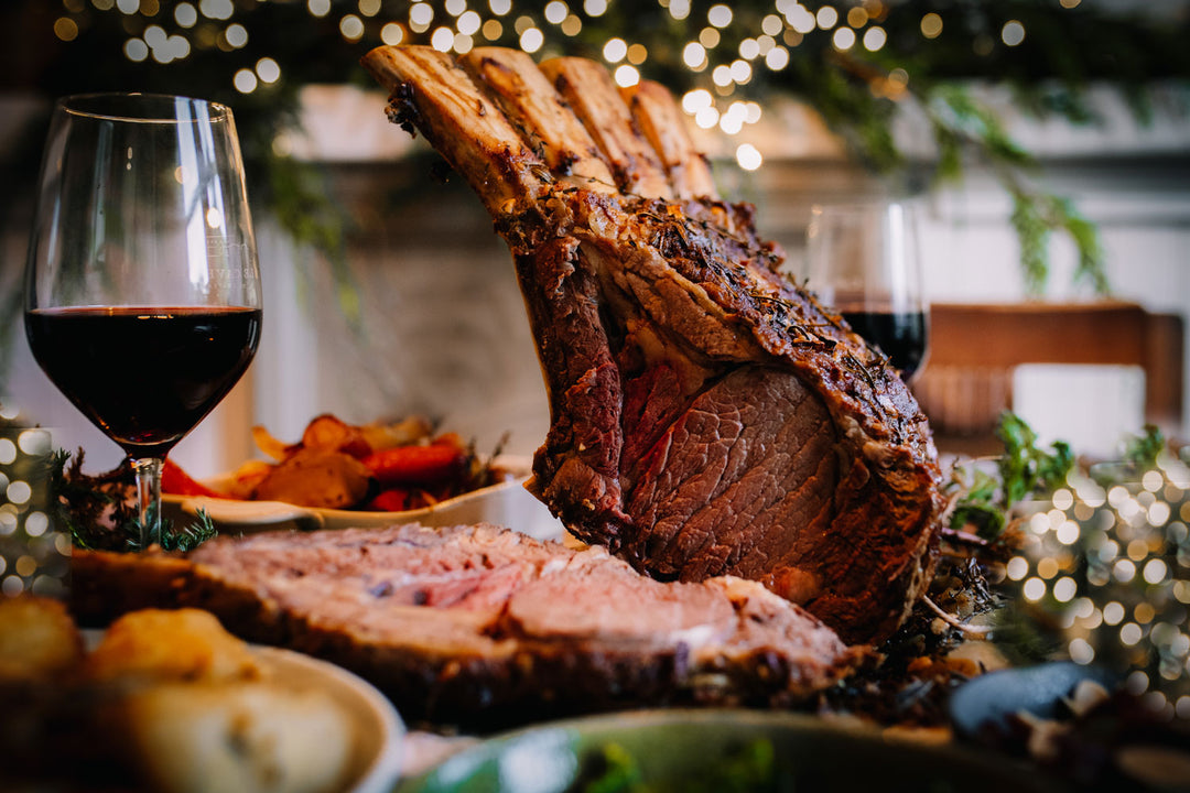 Roast beef with a glass of red wine on a festive table with blurred lights in the background
