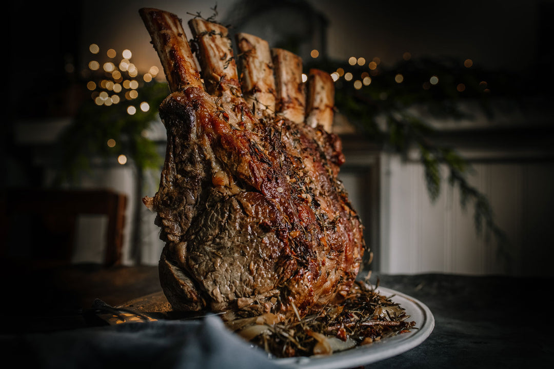 Roasted bone in rib roast of beef on a platter with a festive background