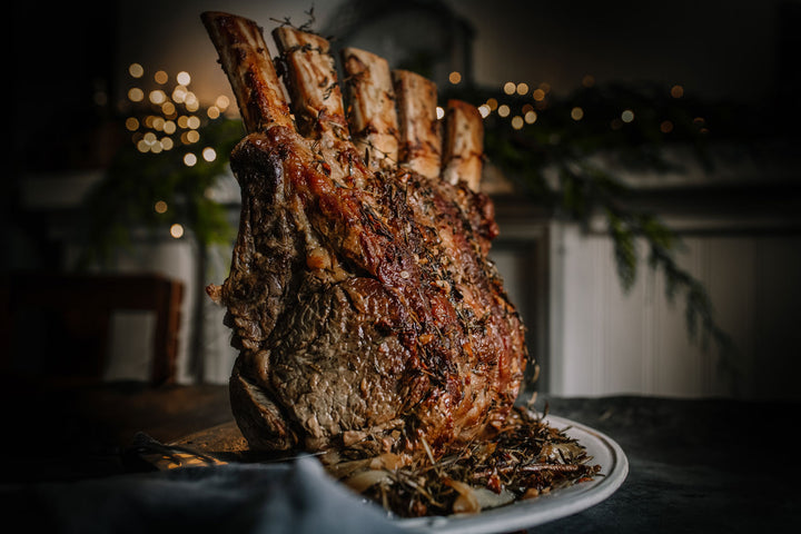 Roasted bone in rib roast of beef on a platter with a festive background